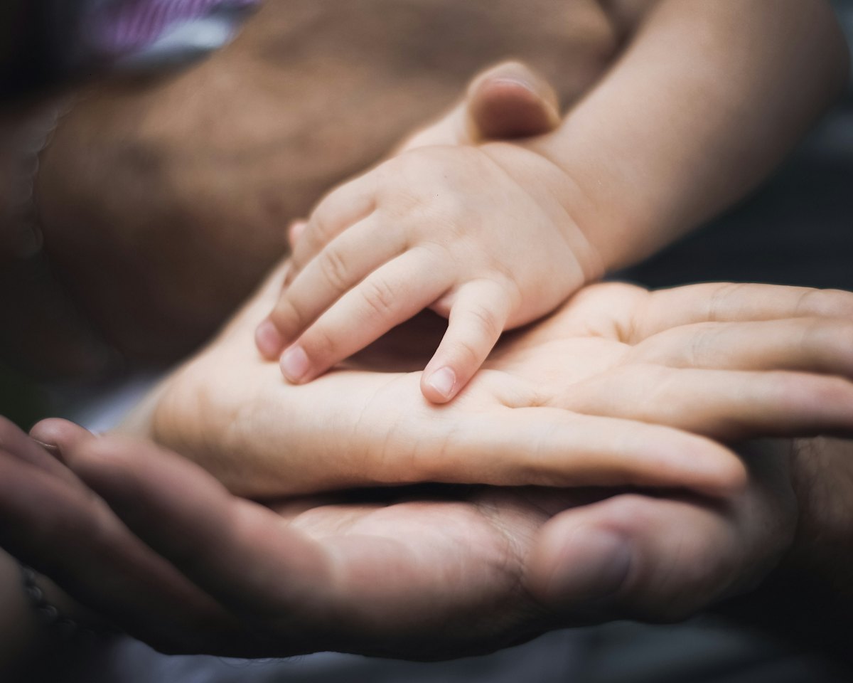La mano di un bambino appoggiata su quella di un adulto